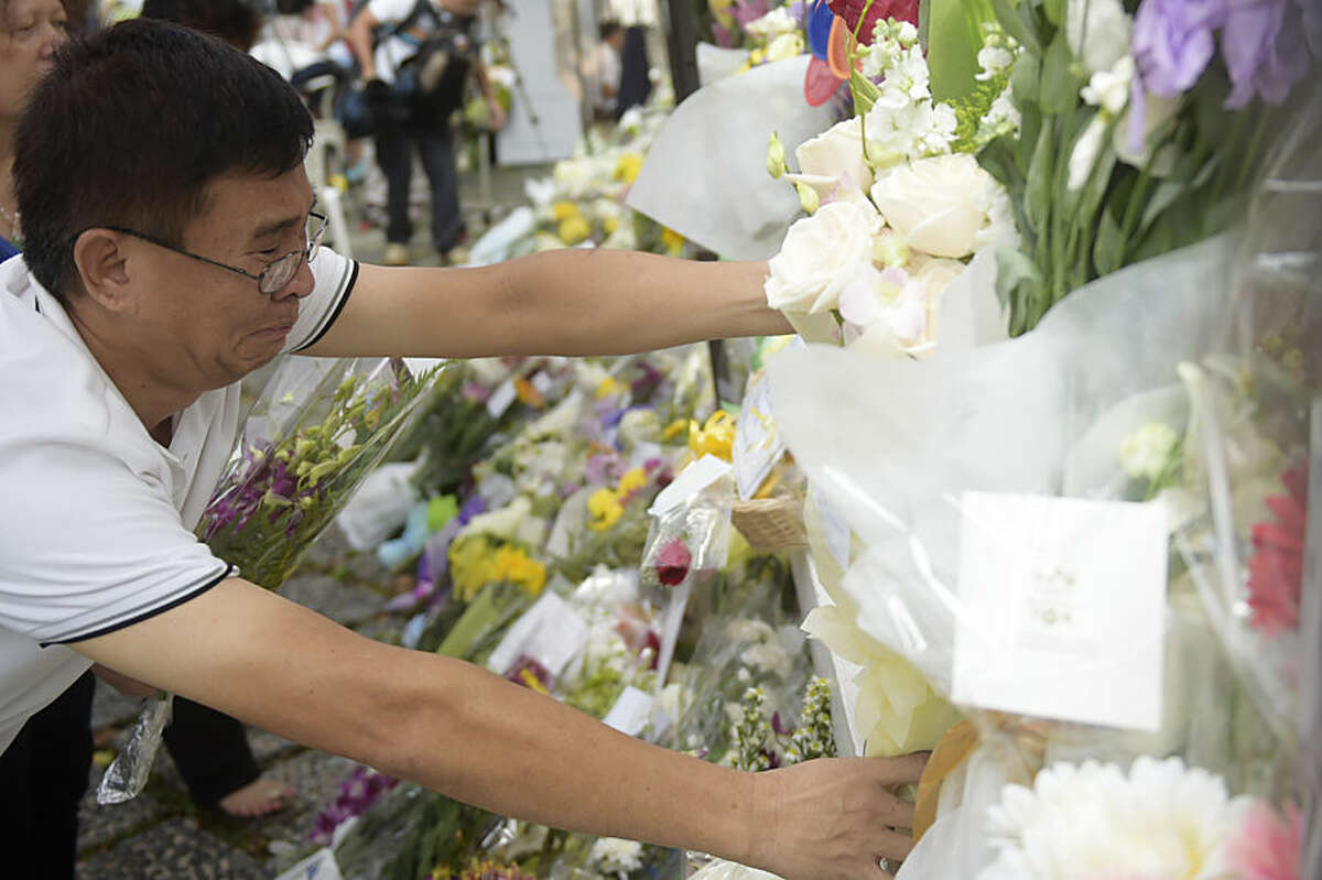 Mourner Chew Lian San breaks down as he tries to arrange flowers at the gate of Istana or presidential palace, in Singapore Tuesday, March 24, 2015, a day after the death of Singapore's founding father Lee Kuan Yew. Singapore mourned longtime leader Lee with raw emotion and a blanket of relentlessly positive coverage on its tightly scripted state television on Monday, mythologizing a man who was as respected as he was feared. (AP Photo/Joseph Nair)