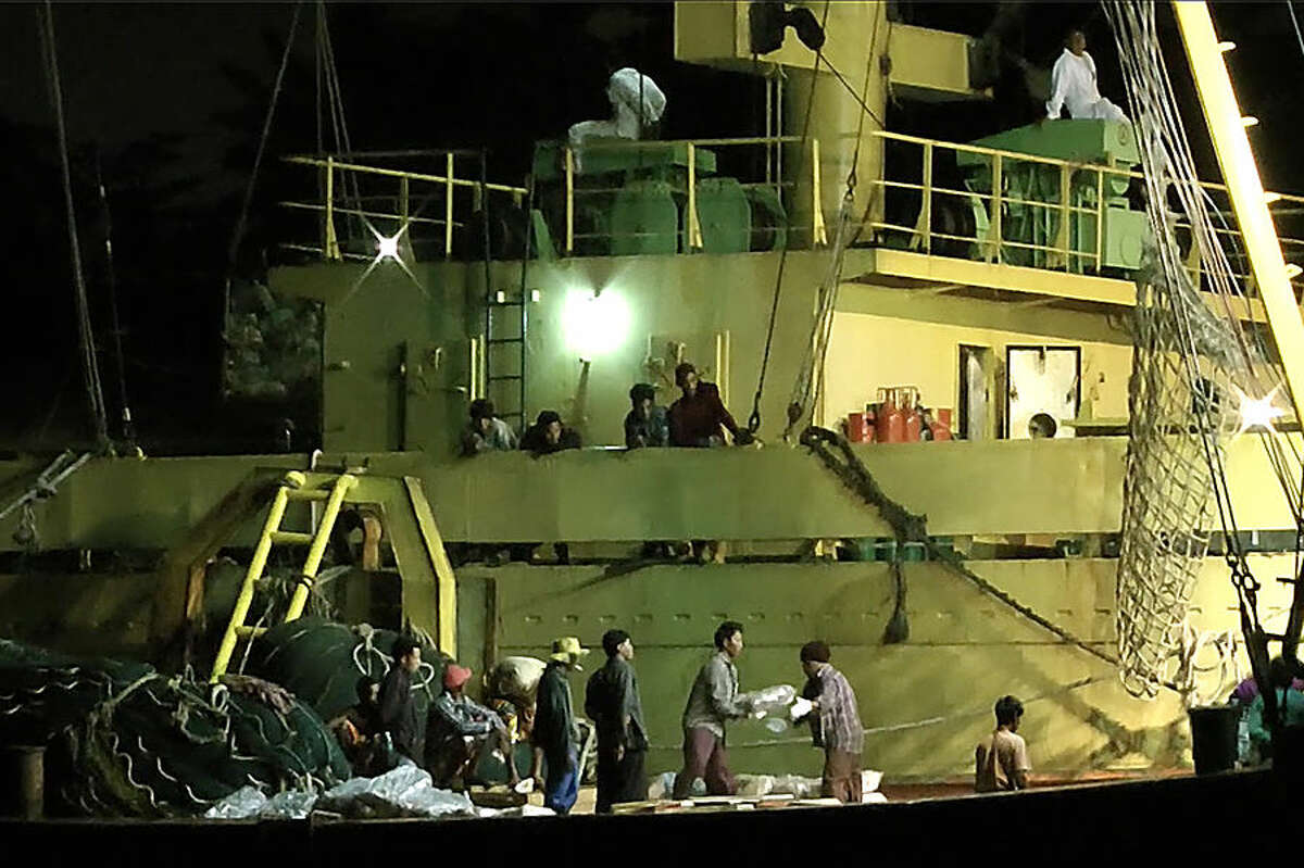 In this Thursday, Nov. 27, 2014 image from video, workers from Myanmar load fish onto a Thai-flagged cargo ship in Benjina, Indonesia. An intricate web of connections separates the fish we eat from the men who catch it, and obscures a brutal truth: Your seafood may come from slaves. (AP Photo/APTN)