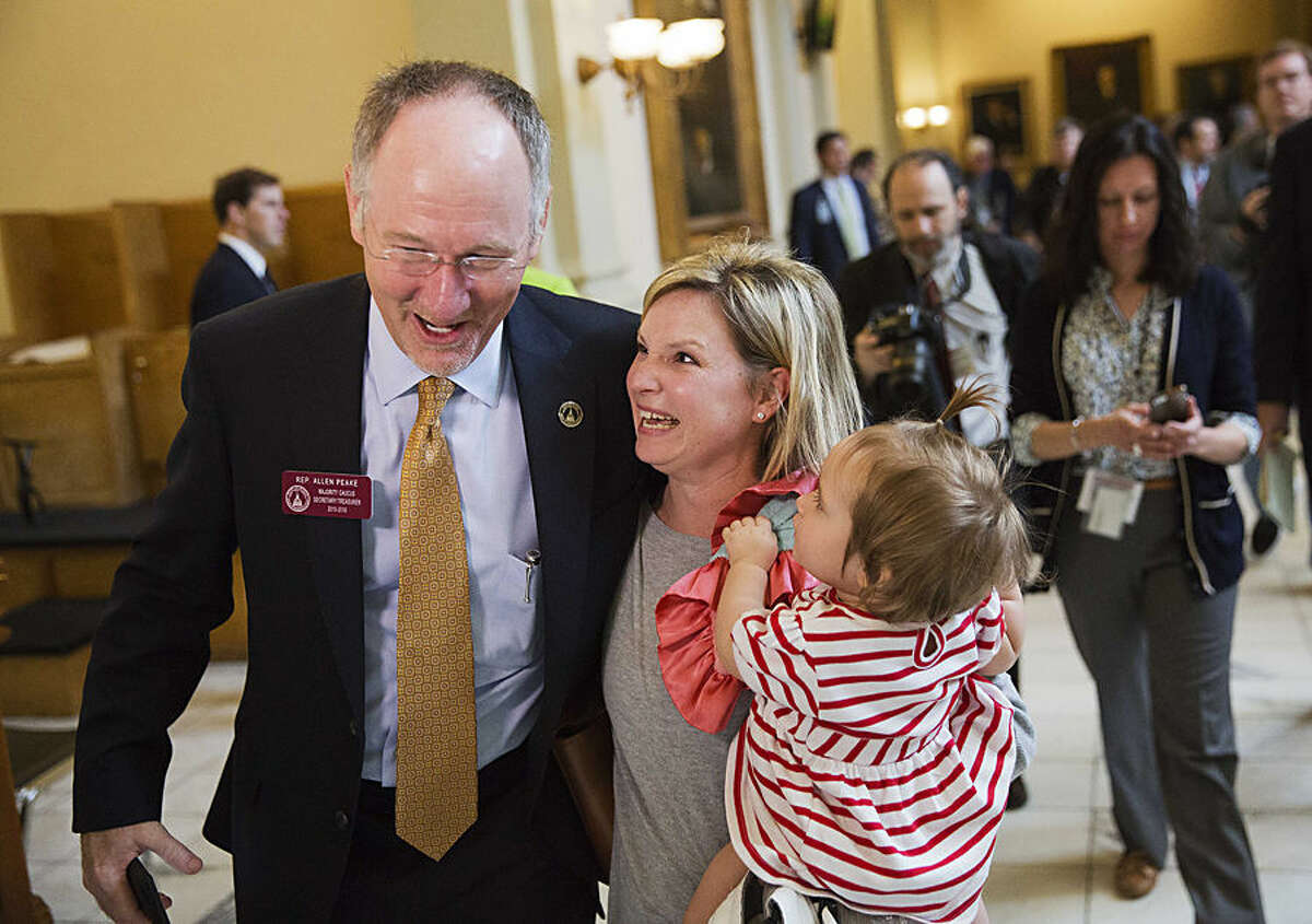 State Rep. Allen Peake, R-Macon, left, celebrates with Kristi Baggarly, holding her daughter Kimber, 1, as they walk through the Capitol after the Senate approved Peake's medical marijuana bill Tuesday, March 24, 2015, in Atlanta. The bill will legalize possession of cannabis oil for treatment of certain medical conditions, like for Baggarly's other daughter Kendle, who suffers from seizures. (AP Photo/David Goldman)