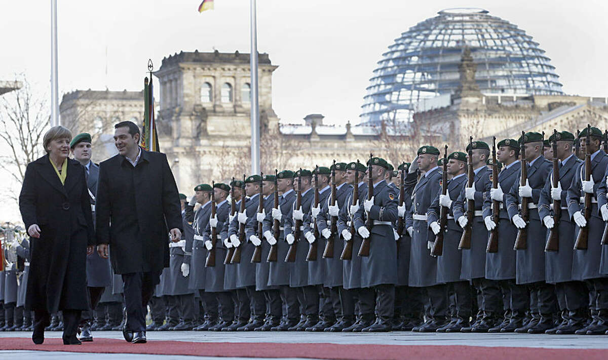 German Chancellor Angela Merkel, left, welcomes the Prime Minister of Greece Alexis Tsipras, right, with military honors at the chancellery in Berlin, Germany, Monday, March 23, 2015. Building in the background is the Reichstag that hosts the German parliament. (AP Photo/Michael Sohn)