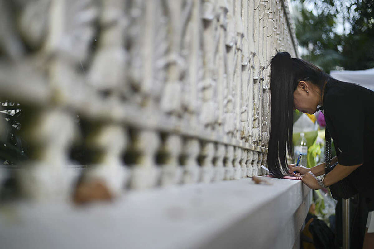 A mourner writes a condolence message at Istana, or Presidential Palace, where a private wake for the late Lee Kuan Yew is being held, in Singapore Tuesday, March 24, 2015. Singapore mourned longtime leader Lee with raw emotion and a blanket of relentlessly positive coverage on its tightly scripted state television on Monday, mythologizing a man who was as respected as he was feared. (AP Photo/Joseph Nair)