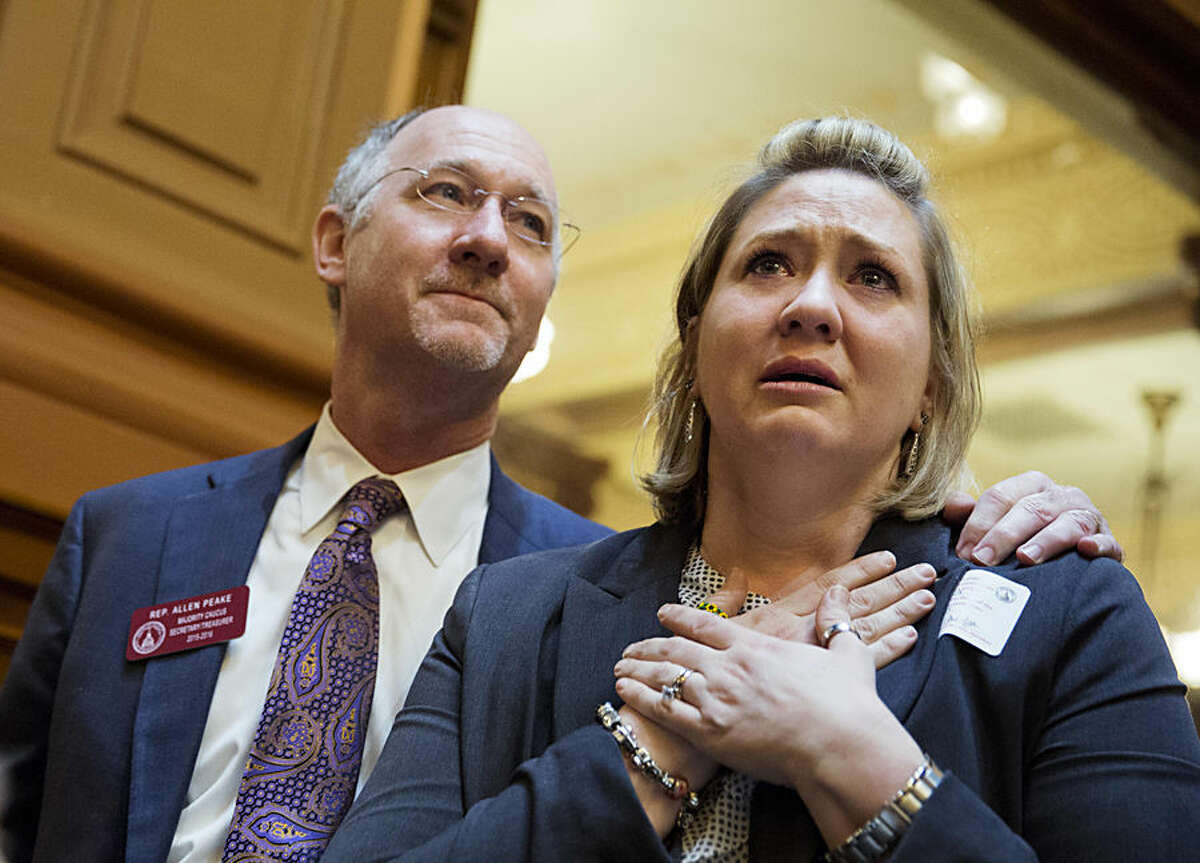 Janea Cox, right, whose daughter Haleigh suffers seizures, watches with Rep. Allen Peake, R-Macon, as the House approves "Haleigh's Hope Act," a bill legalizing possession of cannabis oil for treatment of certain medical conditions Wednesday, March 25, 2015, in Atlanta. House lawmakers agreed, 160-1, Wednesday to the compromise measure sending the bill to Georgia Gov. Nathan Deal after a two-year legislative battle. Peake hopes the measure will convince 17 Georgia families with sick children to return from Colorado, where marijuana is legal. (AP Photo/David Goldman)