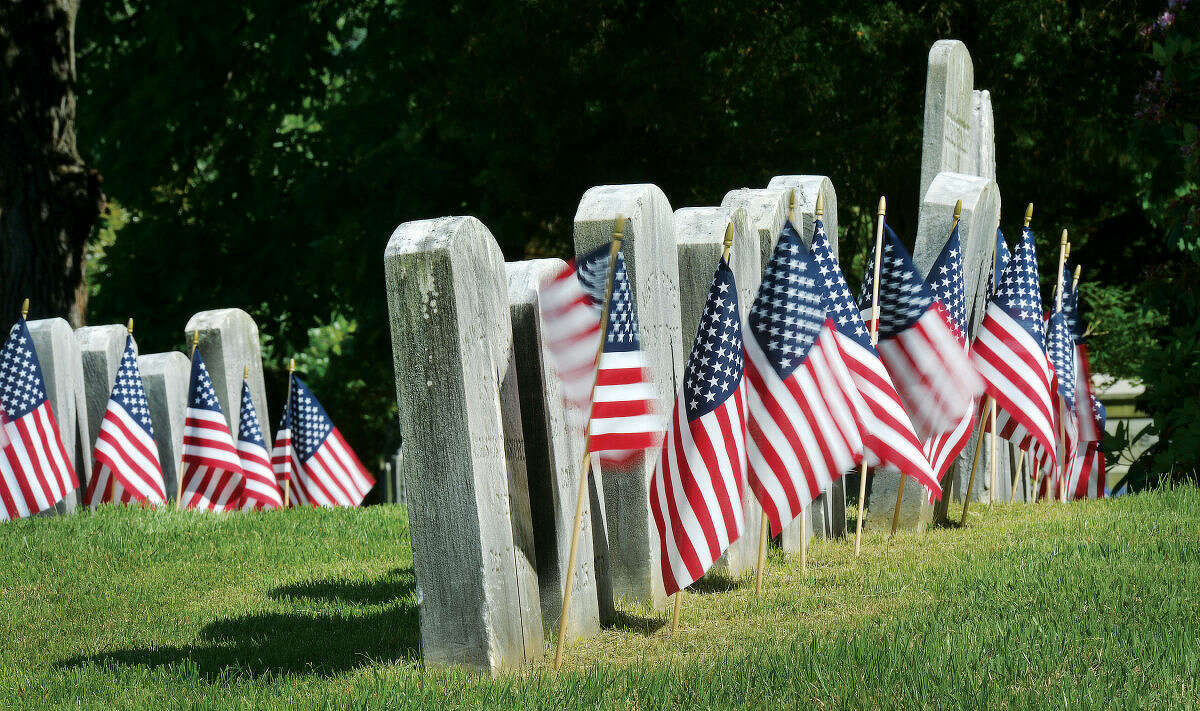 Hour File Photo/Alex von Kleydorff . Under bright skies, flags wave in the wind in front of rows of veterans headstones in Riverside Cemetery