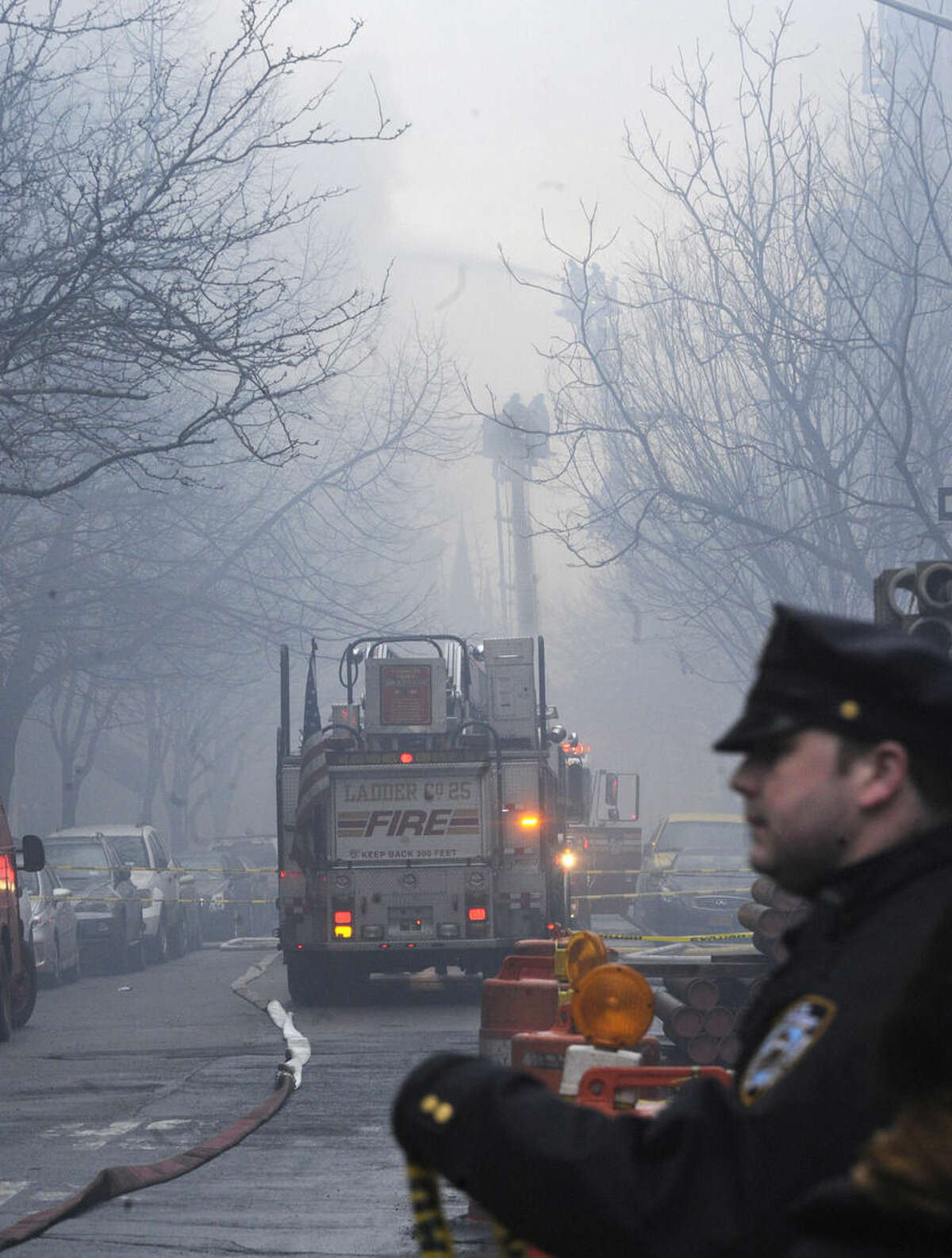 New York City firefighters arrive at the scene of a large fire and a partial building collapse in the East Village neighborhood of New York on Thursday, March 26, 2015. Orange flames and black smoke are billowing from the facade and roof of the building near several New York University buildings. (AP Photo/ Louis Lanzano)