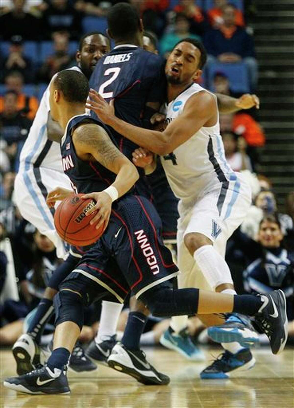 Villanova's Darrun Hilliard II (4) runs into a pick set by Connecticut's DeAndre Daniels (2) as he chases Shabazz Napier during the first half of a third-round game in the NCAA men's college basketball tournament in Buffalo, N.Y., Saturday, March 22, 2014. (AP Photo/Bill Wippert)