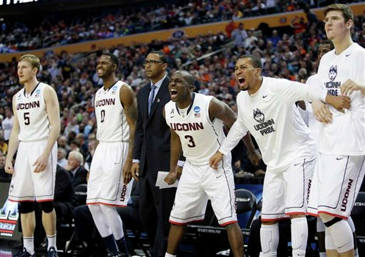 Connecticut's Terrence Samuel (3) joins teammates Niels Giffey (5) and Phillip Nolan (0) as he cheers during overtime of a second-round game against Saint Joseph's in the NCAA college basketball tournament in Buffalo, N.Y., Thursday, March 20, 2014. Connecticut won 89-81. (AP Photo/Nick LoVerde)
