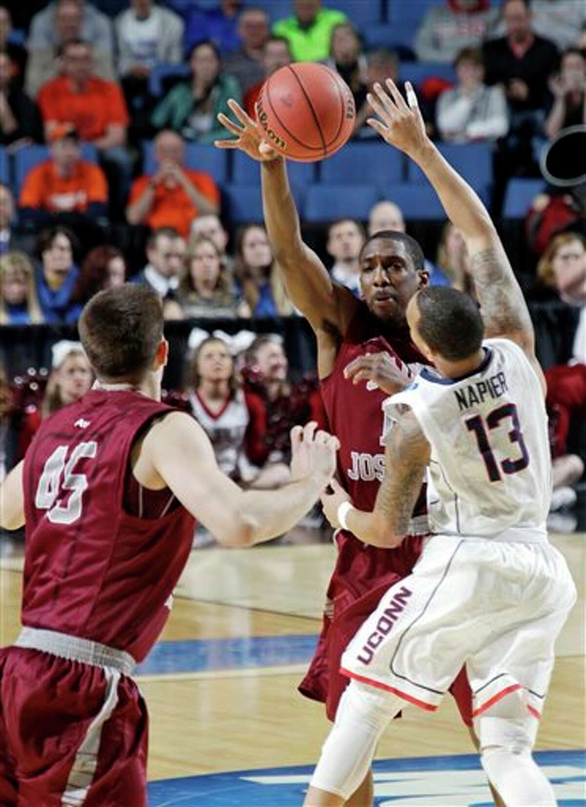 Saint Joseph's Ronald Roberts, Jr., center, passes the ball away from Connecticut's Shabazz Napier (13) to teammate Halil Kanacevic (45) during the first half of a second-round game in the NCAA college basketball tournament in Buffalo, N.Y., Thursday, March 20, 2014. (AP Photo/Bill Wippert)
