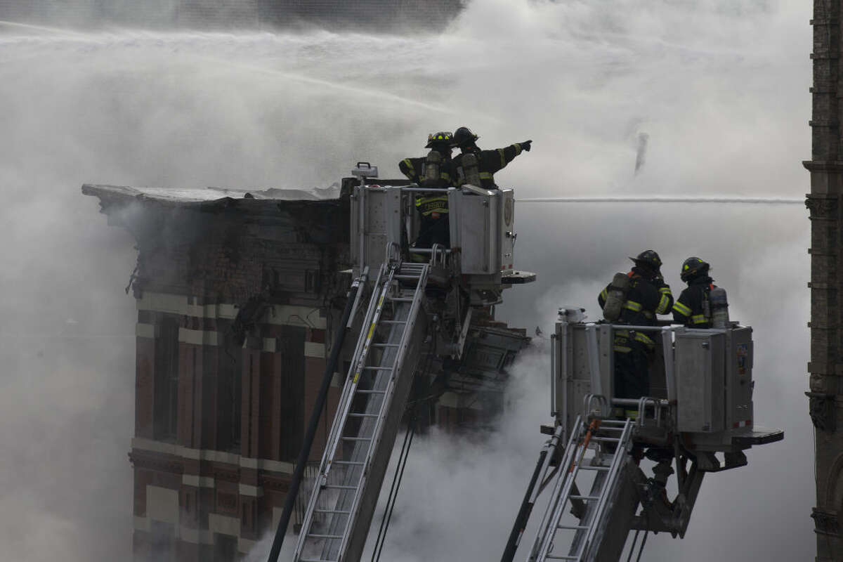 New York City firefighters work the scene of a large fire and a partial building collapse in the East Village neighborhood of New York on Thursday, March 26, 2015. Orange flames and black smoke are billowing from the facade and roof of the building near several New York University buildings. (AP Photo/John Minchillo)