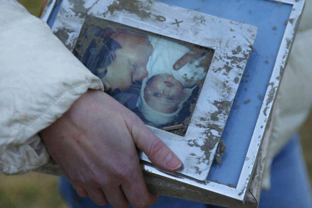 A woman holds family photos pulled from the rubble at the site of Saturday's fatal mudslide near Oso, Wash., Sunday, March 23, 2014. (AP Photo /The Herald, Genna Martin)