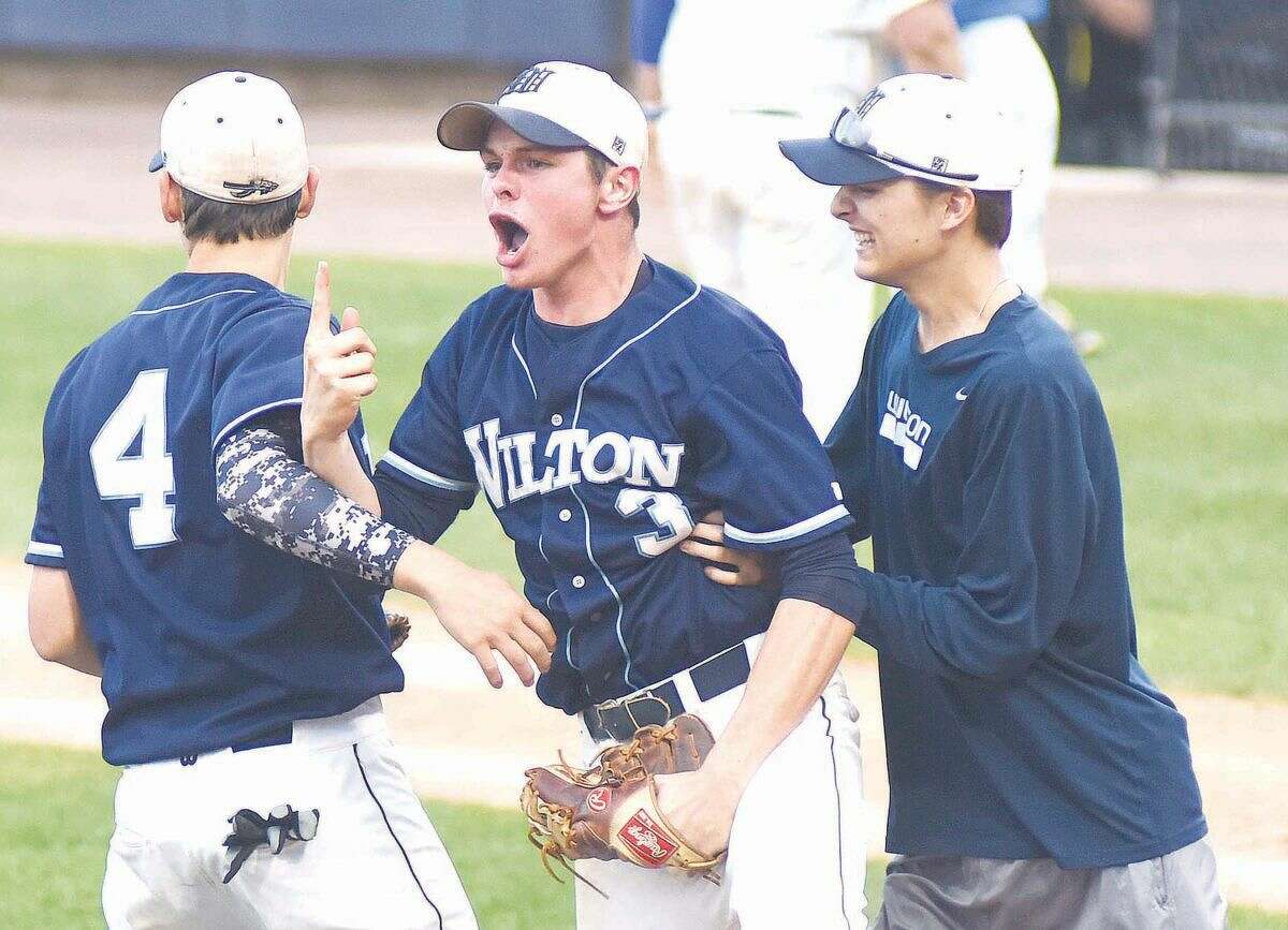 Wilton starting pitcher Jackson Ward, center, signals that his team needs one more win to earn the FCIAC championship after earning a 5-1 win over Darien in the league semifinals at The Ballpark at Harbor Yard on Wednesday. Ward struck out 11 and walked one in a complete-game win.