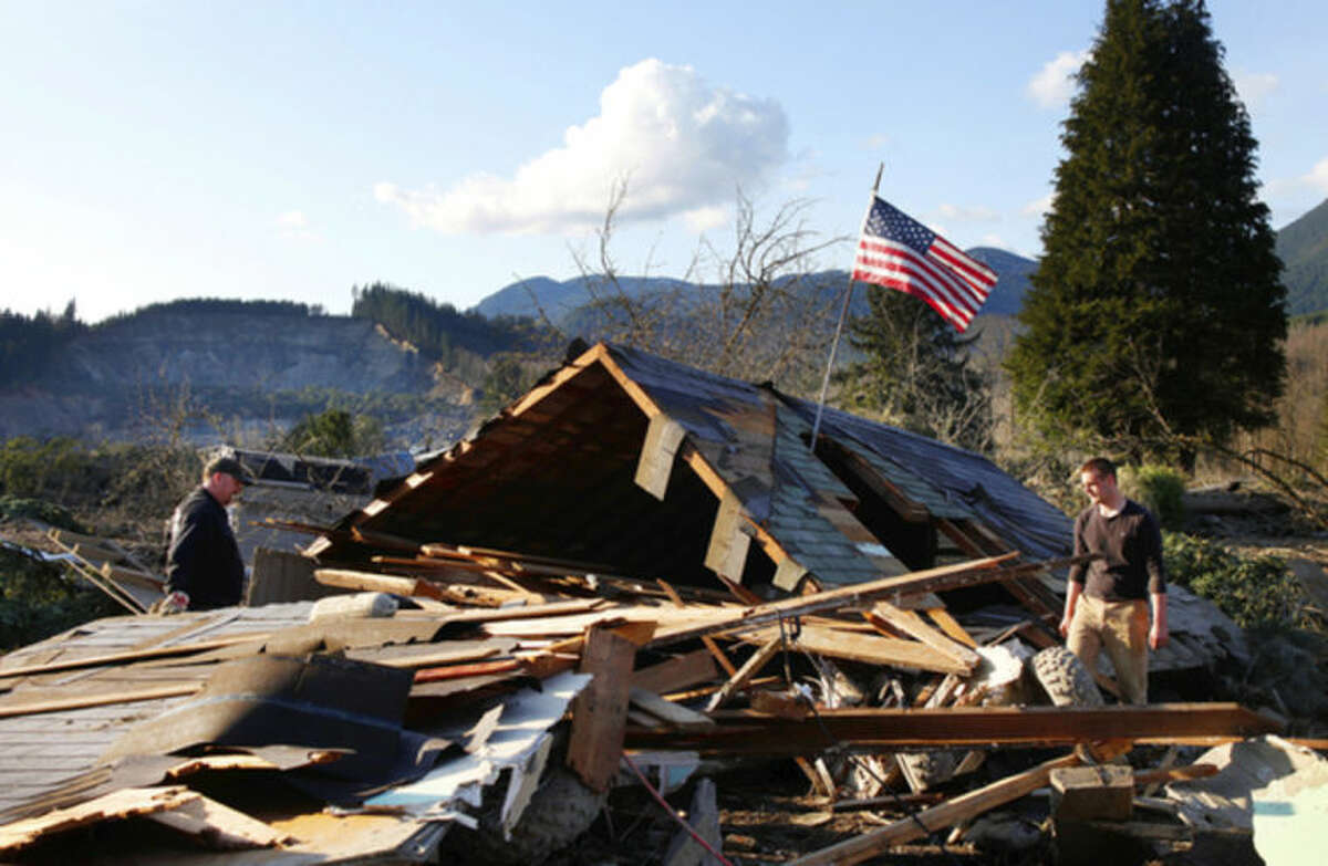 Brian Anderson, left, and Coby Young search through the wreckage of a home belonging to the Kuntz family Sunday, March 23, 2014, near Oso, Wash. The entire Kuntz family was at a baseball game Saturday morning when a fatal mudslide swept through the area. The family returned Sunday to search through what remained. (AP Photo /The Herald, Genna Martin)