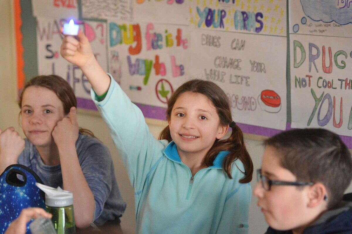 Hour Photo/Alex von Kleydorff West Rocks school 6th grader Rachel Lasky along with other students light an electronic blue colored candle to draw attenetion to World Autism Awareness Day.