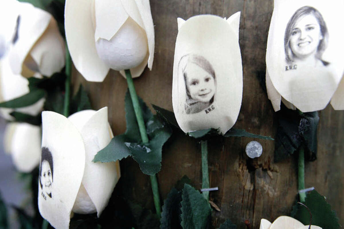 AP photo / Seth Wenig Photos showing victims of shootings at Sandy Hook Elementary School are imprinted on fake roses at a memorial in the village of Newtown Saturday.