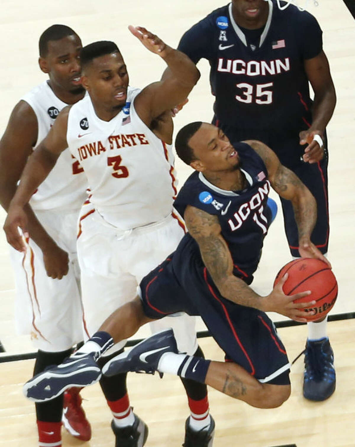 Connecticut's Ryan Boatright drives near Iowa State's Melvin Ejim, center, and Dustin Hogue, left, during the second half in a regional semifinal of the NCAA men's college basketball tournament Friday, March 28, 2014, in New York. (AP Photo/Julio Cortez)