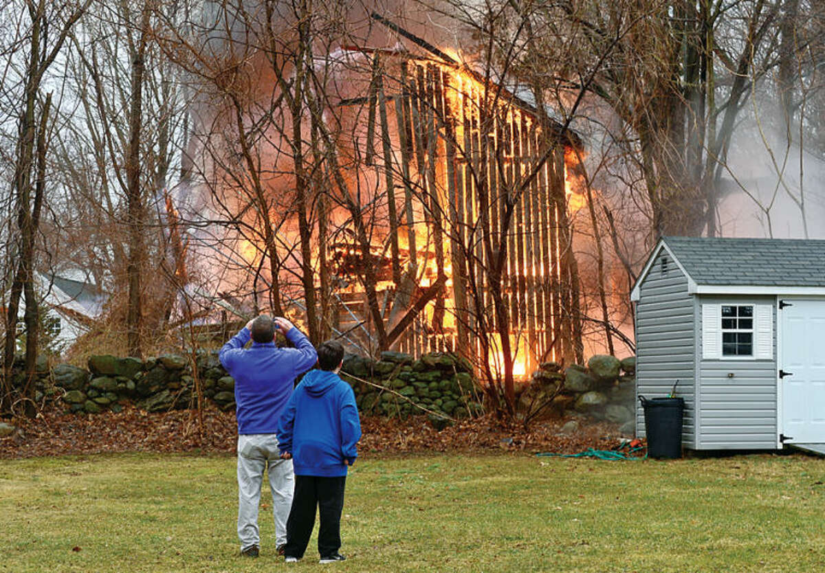 Hour photo / Erik Trautmann Jerry Quinn and his son Connor watch as a barn at 44 Fox Run Rd in Norwalk is destroyed by fire Saturday afternoon.