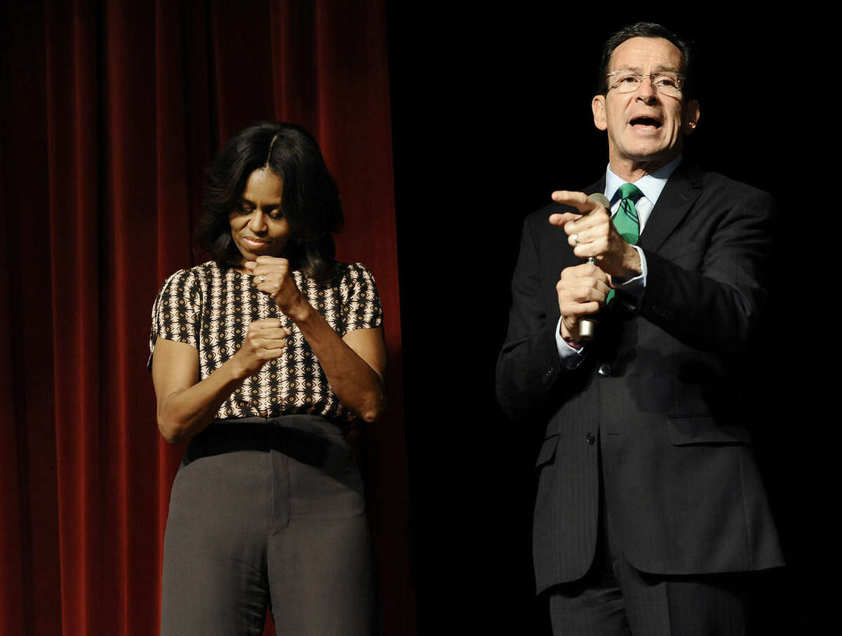 First Lady Michelle Obama, left, pumps her fists as Connecticut Gov. Dannel P. Malloy speaks to a surprised group of supporters in an overflow room before a rally, Thursday, Oct. 30, 2014, in New Haven, Conn. (AP Photo/Jessica Hill, Pool)