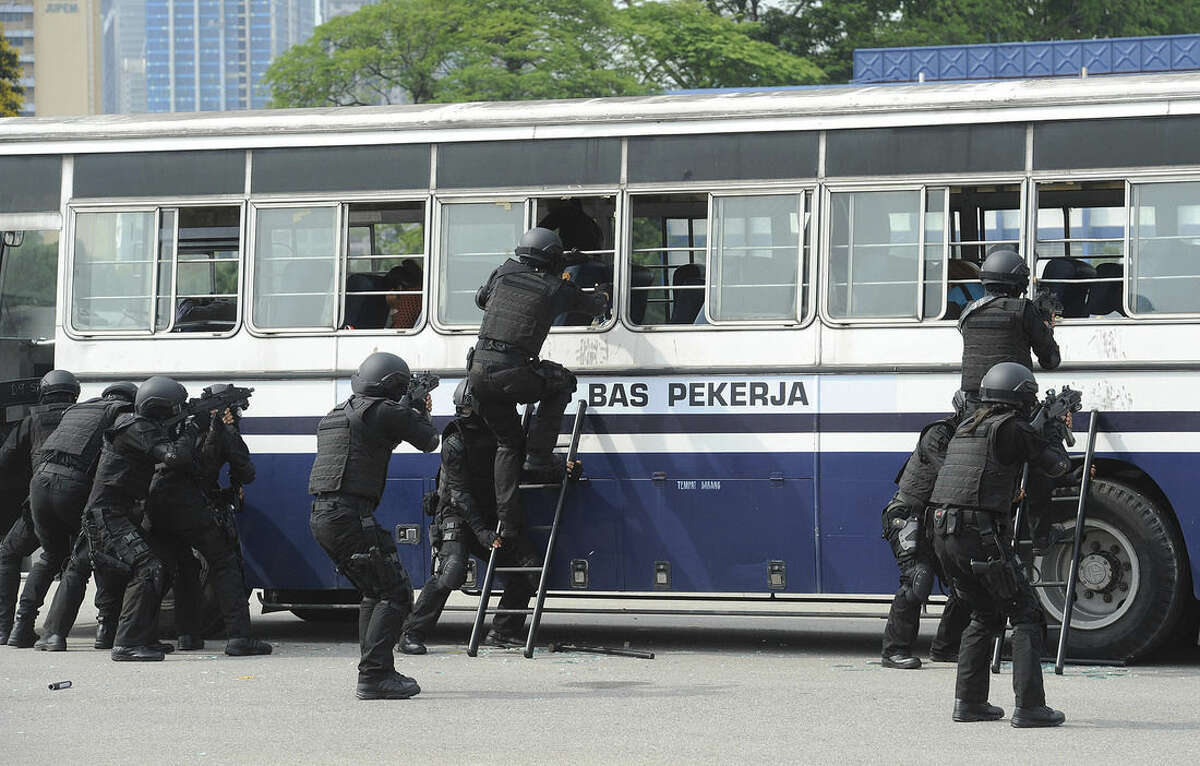 In this Wednesday, March 25, 2015 photo, Malaysia Police special force unit tries to break into a bus during an exercise against a terrorist attack at a police training camp in Kuala Lumpur, Malaysia. Malaysia revived detention without trial when lawmakers approved an anti-terror law Tuesday, April 7, 2015 that the government said was needed to fight Islamic militants, but critics assailed as a giant step backward for human rights in the country. (AP Photo) MALAYSIA OUT, NO SALES, NO ARCHIVE
