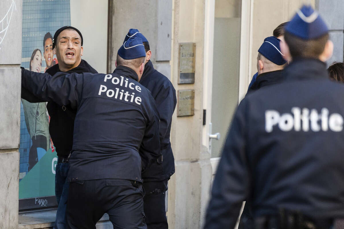 Police officers detain a man in the historic center in Brussels on Thursday, Dec. 31, 2015. The New Year's Eve fireworks display and all official events are being canceled in Belgium's capital due to threats of an extremist attack. It was not known why the man was detained. (AP Photo/Geert Vanden Wijngaert)