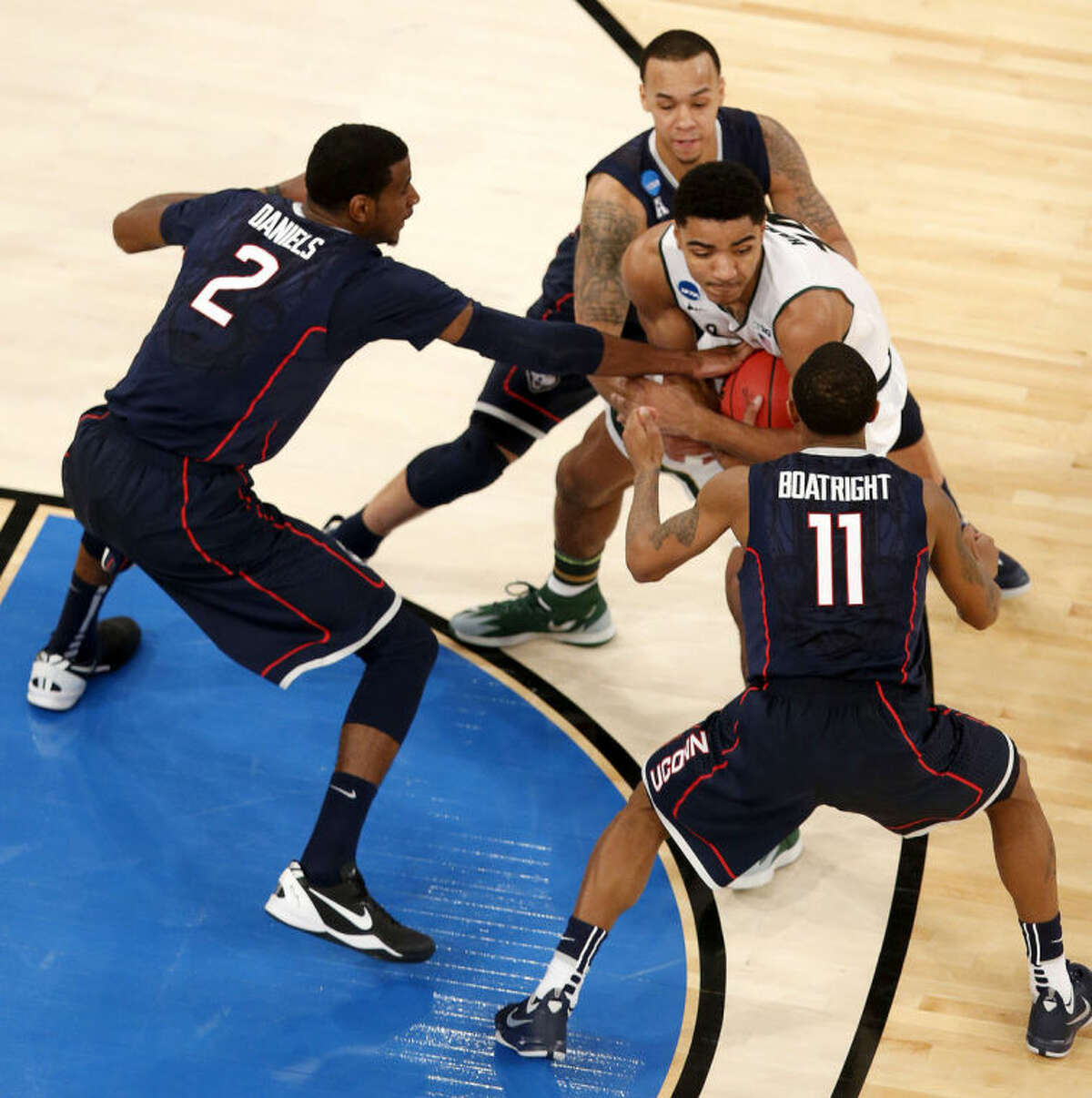 Michigan State guard Gary Harris, center, fights off Connecticut forward DeAndre Daniels (2), guard Ryan Boatright (11) and guard Shabazz Napier during the second half in a regional semifinal at the NCAA college basketball tournament on Sunday, March 30, 2014, in New York. (AP Photo/Julio Cortez)