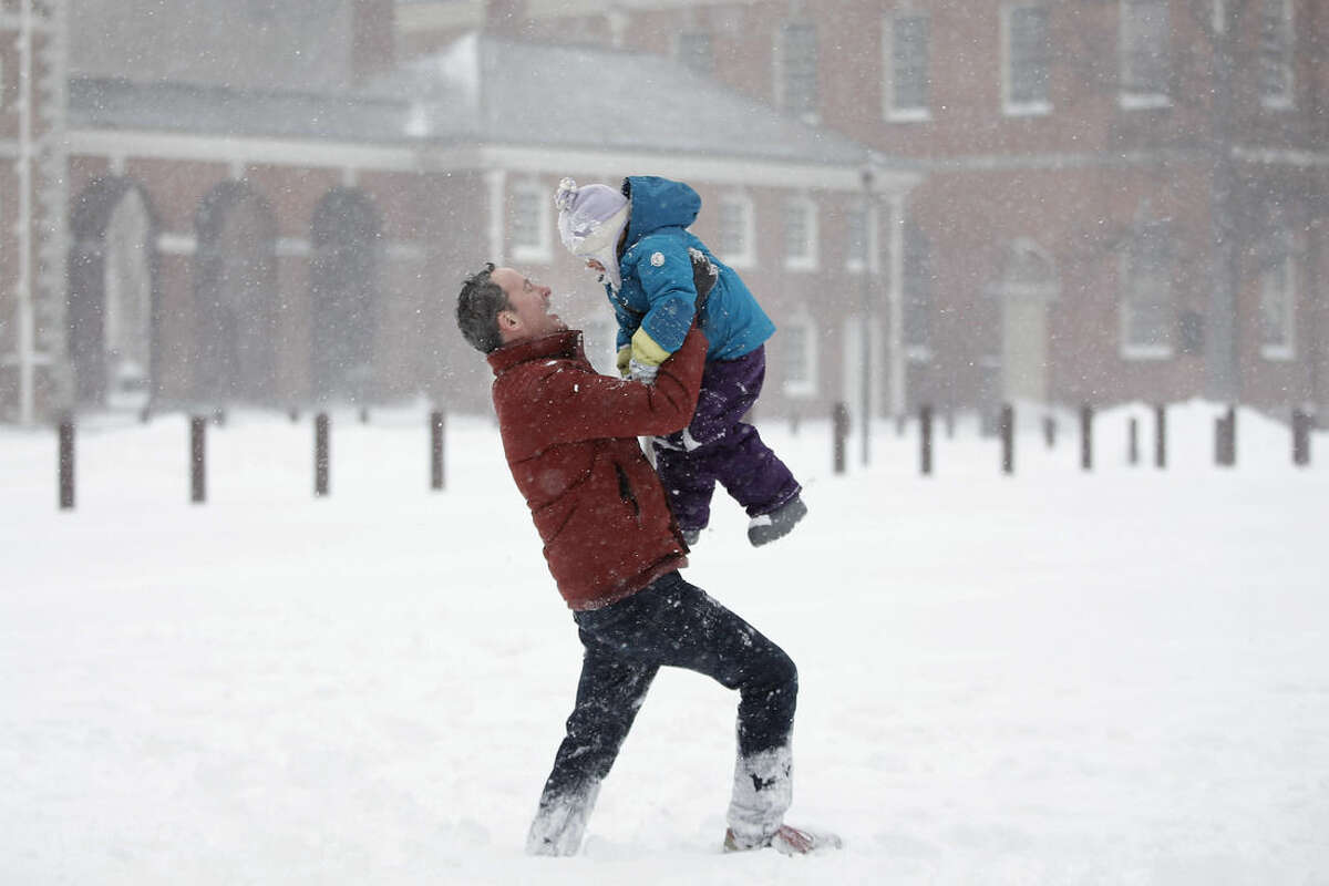 Dan Rafalin, left, lifts his daughter, Delila Rafalin, 5, while playing in heavy snowfall with their family on Independence Mall, Saturday, Jan. 23, 2016, in Philadelphia. (AP Photo/Matt Slocum)