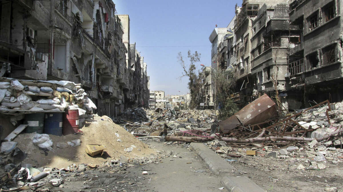 FILE - This Feb. 24, 2014, file photo released by the United Nations Relief and Works Agency for Palestine Refugees in the Near East (UNRWA) shows damage and debris on one of the main streets of the besieged Palestinian camp of Yarmouk in Damascus, Syria. Yarmouk was established in 1957 as a refuge for Palestinians who were forced out of their homes with the 1948 creation of Israel, and expanded with time to include thousands of Syrians as well. (AP Photo/UNRWA, File)