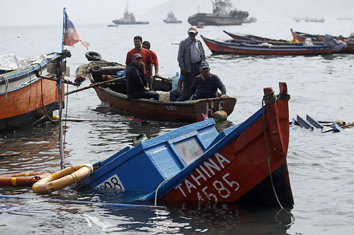 Fishermen look for boats to salvage damaged overnight in the port of Iquique, Chile, Wednesday, April 2, 2014. Chilean authorities discovered surprisingly light damage Wednesday from a magnitude-8.2 quake that struck in the Pacific Ocean, Tuesday evening, near the mining port of Iquique, a northern coastal city of nearly 200,000 people. Fishing boats were lifted onto city streets and others were sunk in the port. Six deaths have been reported. ( AP Photo/ Luis Hidalgo, Pool)