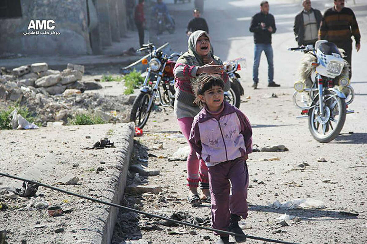 In this photo taken on Wednesday April 2, 2014 provided by the anti-government activist group Aleppo Media Center (AMC), an anti-Bashar Assad activist group, which has been authenticated based on its contents and other AP reporting, shows Syrian girls reacting after a government airstrike attack on their neighborhood, in Aleppo, Syria. (AP Photo/Aleppo Media Center, AMC)