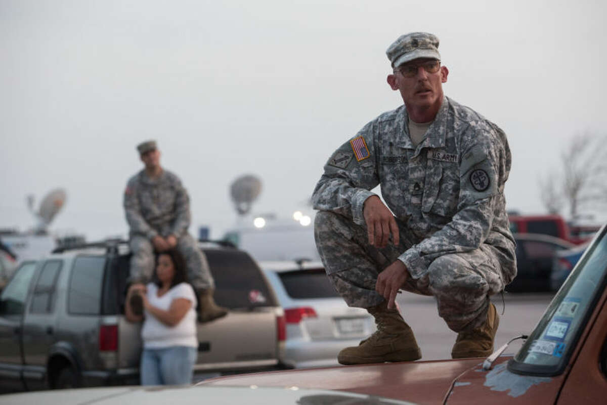 Staff Sgt. John Robertson, right, waits in a parking lot outside of the Fort Hood military base for updates about the shooting that occurred inside on Wednesday, April 2, 2014, in Fort Hood, Texas. (AP Photo/Tamir Kalifa)