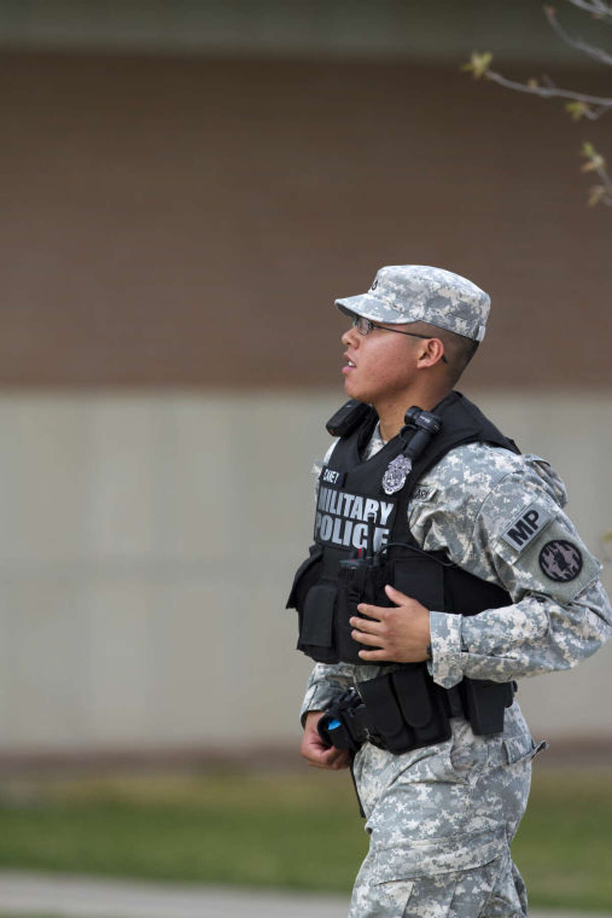 A Military Police officer runs toward the road leading to the Main Gate, Wednesday, April 2, 2014, as an active shooter remains at large at Fort Hood, Texas. One person was killed and 14 injured in the shooting, and officials at the base said the shooter is believed to be dead. The details about the number of people hurt came from two U.S. officials who spoke on condition of anonymity because they were not authorized to discuss the information by name. (AP Photo/The Temple Daily Telegram, Rusty Schramm)