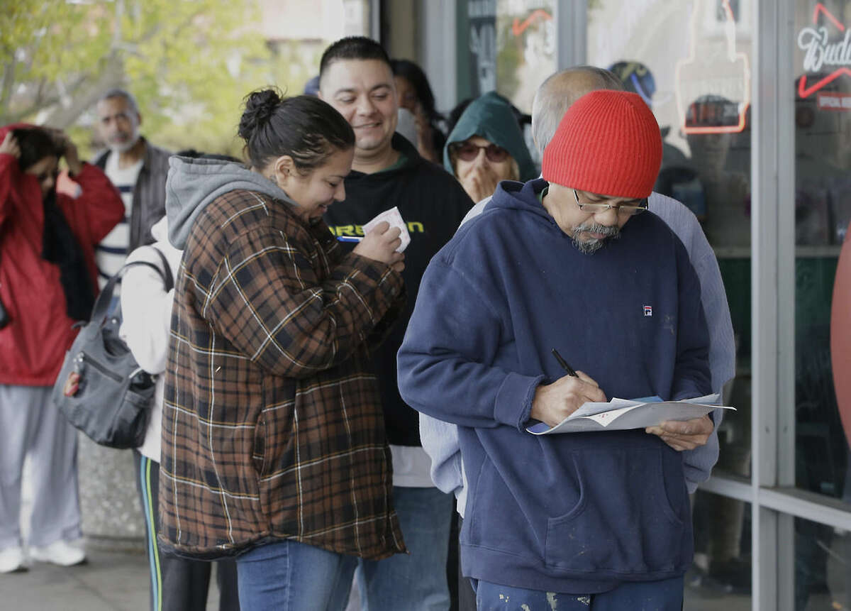 Leo Lopez, right, picks his numbers on a lottery form as he waits in line to purchase Powerball lottery tickets at Lichine's Liquor store, Wednesday, Jan. 13, 2016, in Sacramento, Calif. The Powerball jackpot for Wednesday night's drawing is at least $1.5 billion, the largest lottery jackpot in the world. (AP Photo/Rich Pedroncelli)