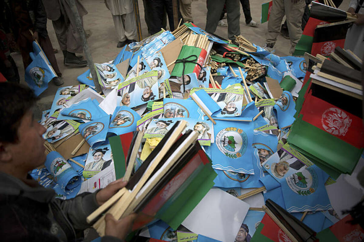 Afghan men collect flags of Afghan presidential candidate Ashraf Ghani Ahmadza outside a stadium where he arrived for an election campaign rally in Kabul, Afghanistan, Tuesday, April 1, 2014. Elections will take place on April 5, 2014. (AP Photo/Anja Niedringhaus)
