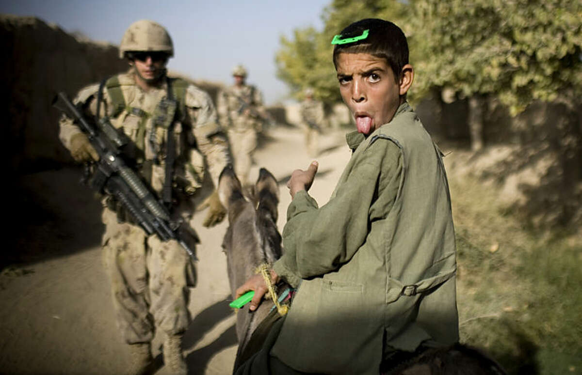 FILE - In this Saturday, Sept. 11, 2010 file photo, an Afghan boy on a donkey reacts as Canadian soldiers with the 1st RCR Battle Group, The Royal Canadian Regiment, patrol in Salavat, southwest of Kandahar, Afghanistan. Minutes later the soldiers were attacked by grenades while leaving the village. Anja Niedringhaus, a courageous and immensely talented Associated Press photographer who has covered everything from sports to war, was killed while covering elections in Afghanistan on Friday April 4, 2014. Niedringhaus was in a car in eastern Afghanistan with AP reporter Kathy Gannon when, according to a freelancer who was with them, an Afghan policeman approached them, yelled "Allahu Akbar" _ God is Great _ and opened fire on them in the back seat with his AK-47. Niedringhaus was killed instantly and Gannon was wounded. (AP Photo/Anja Niedringhaus, File)