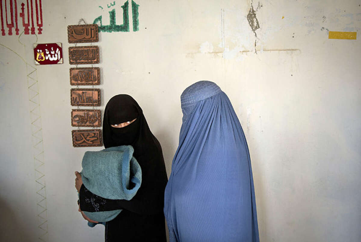 Afghan women with a child queue to get their registration card on the last day of voter registration for the upcoming presidential elections outside a school in Kabul, Afghanistan, Tuesday, April 1, 2014. Elections will take place on April 5, 2014. (AP Photo/Anja Niedringhaus)