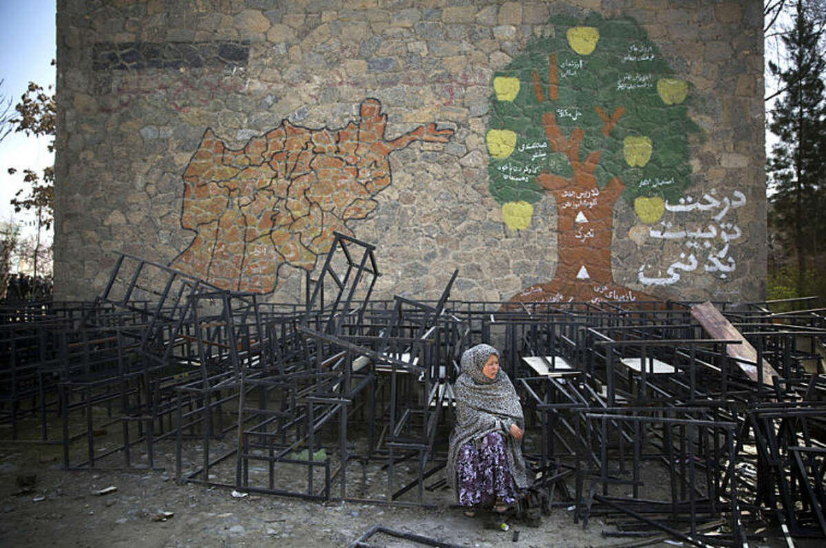 An Afghan woman sits on destroyed school benches as she waits to get her registration card on the last day of voter registration for the upcoming presidential elections outside a school in Kabul, Afghanistan, Tuesday, April 1, 2014. Elections will take place on April 5, 2014. (AP Photo/Anja Niedringhaus)
