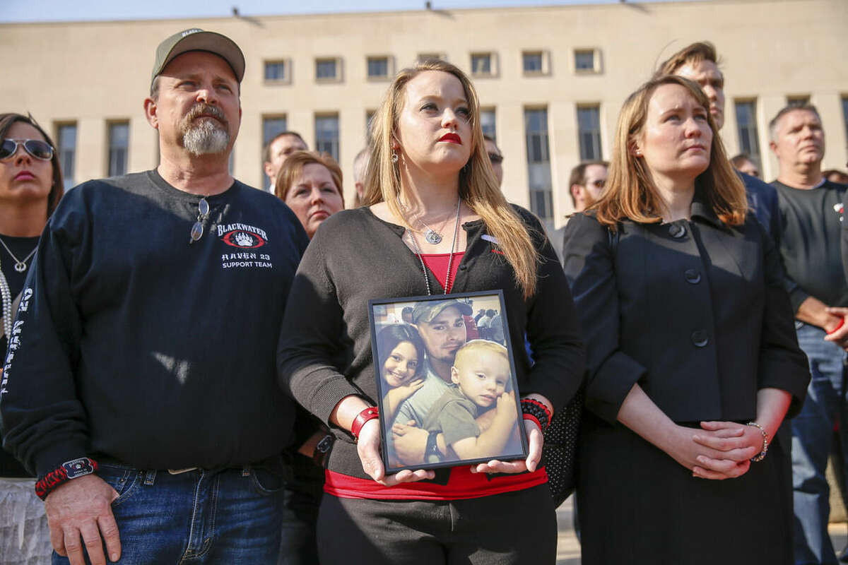 Dustin Heard's wife, Kelli, center, holds a photograph of him and his two children as she stands with other family members, friends, and supporters of four former Blackwater security guards during a press conference outside the Barrett Prettyman Federal Courthouse in Washington, Monday, April 13, 2015, following sentencing for a 2007 shooting of civilians in Iraq. U.S. District Judge Royce Lamberth sentenced Nicholas Slatten to life in prison while Paul Slough of Keller, Texas, Evan Liberty of Rochester, N.H., and Dustin Heard of Knoxville, Tenn., were convicted of manslaughter and received sentences of 30 years plus one day. Also pictured is Stacey Heard, Dustin Heard's father, at left. (AP Photo/Andrew Harnik)