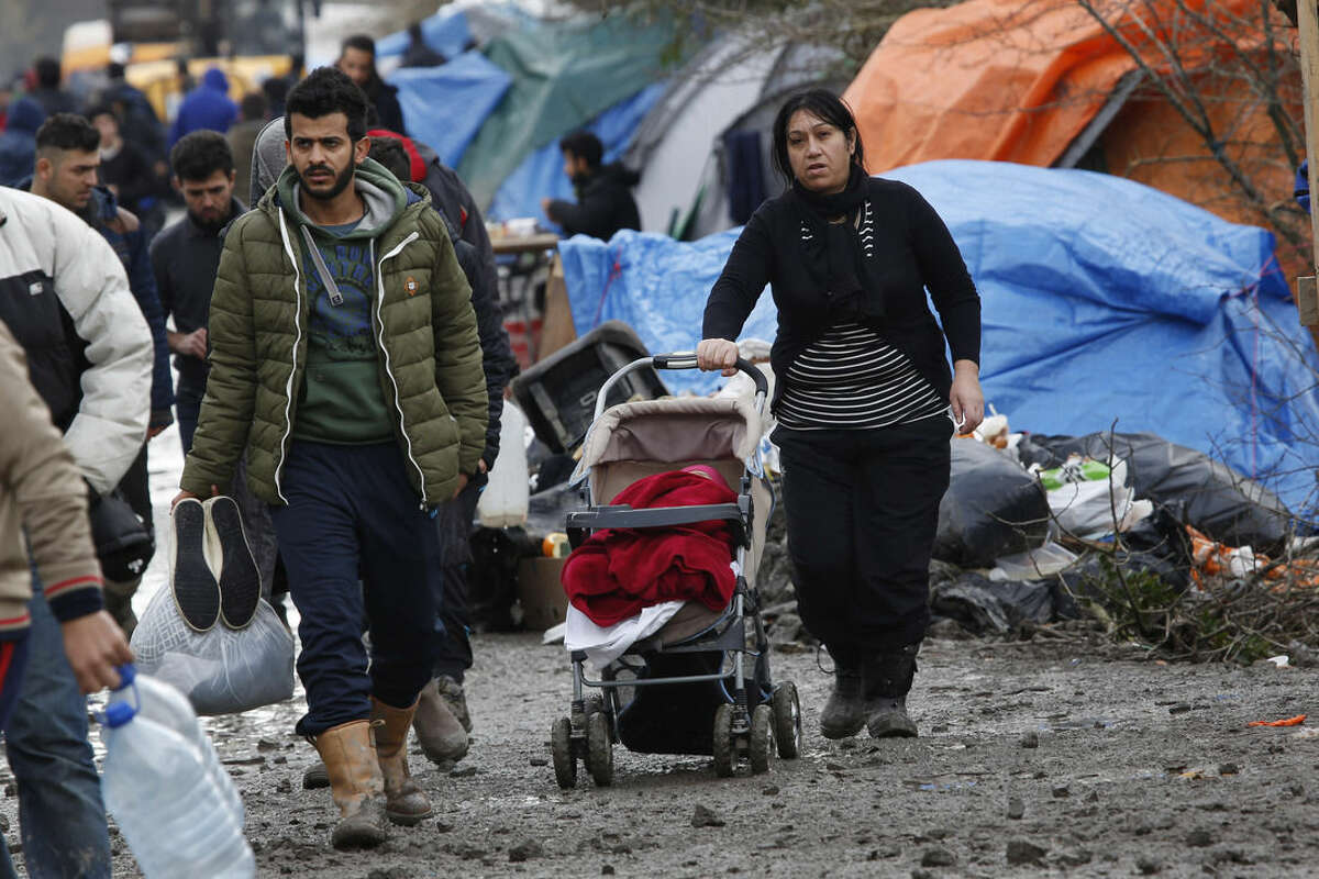 A migrant family walk in the mud in a makeshift camp where over 1,000 migrants mostly from Iraqi Kurdistan live in Grand-Synthe, near the northern town of Dunkerque, France, Wednesday Feb. 24, 2016. The clock is ticking for hundreds of migrants in the nearby port city of Calais waiting for a judge to decide whether to postpone an eviction order in the camp locally referred to as "the jungle". (AP Photo/Jerome Delay)