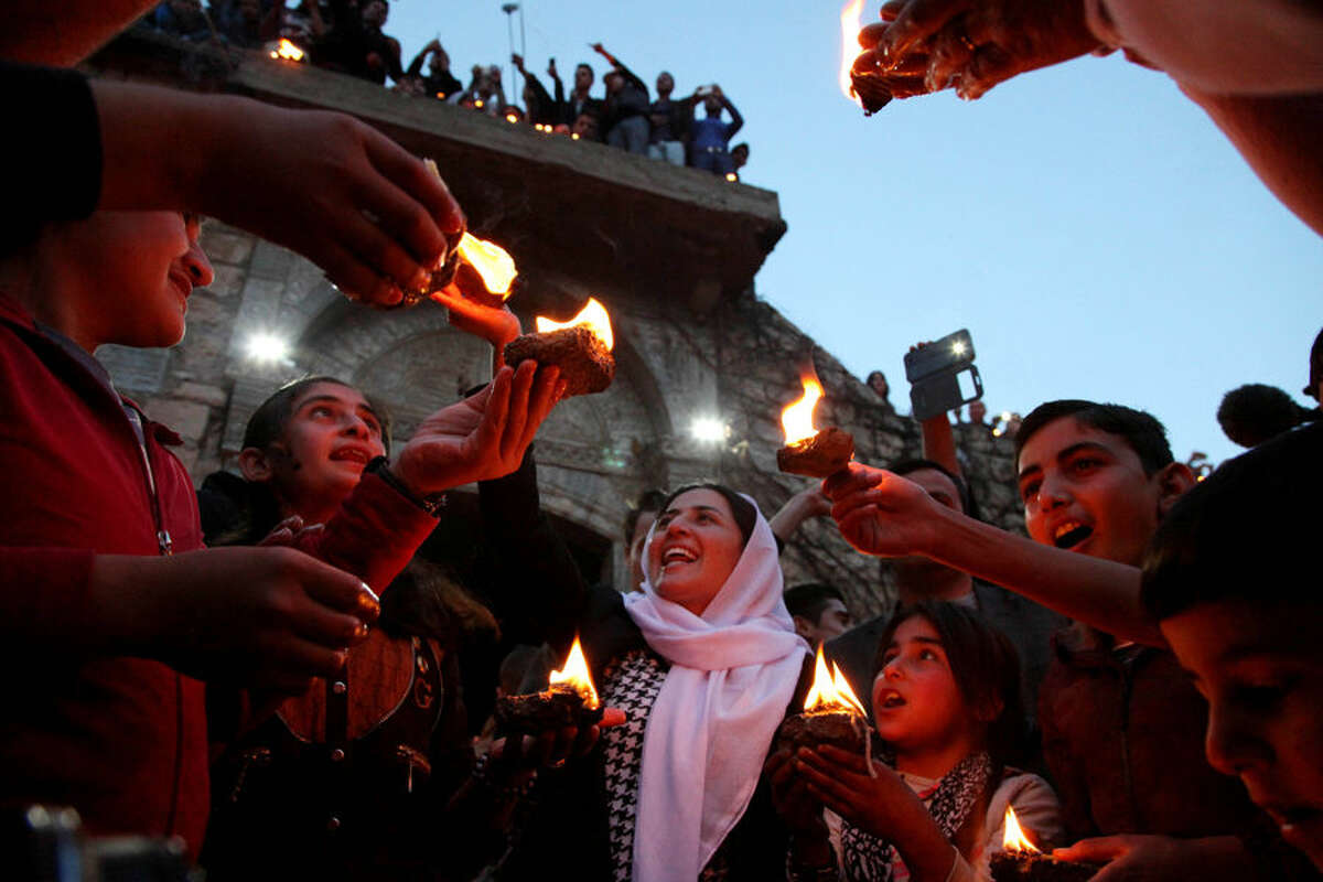 In this Tuesday, April 15, 2015 photo, Yazidis gather at the holy shrine of Lalish, 57 kilometers (35 miles) north of militant-held Mosul, Iraq, as thousands celebrate the New Year, their first since Islamic State militants swept through the area last summer. The Islamic State militants view Yazidis as apostates, departing from their radical interpretation of Islam, and demanded that they convert to Islam or pay a religious fine. (AP Photo/Seivan M.Salim)