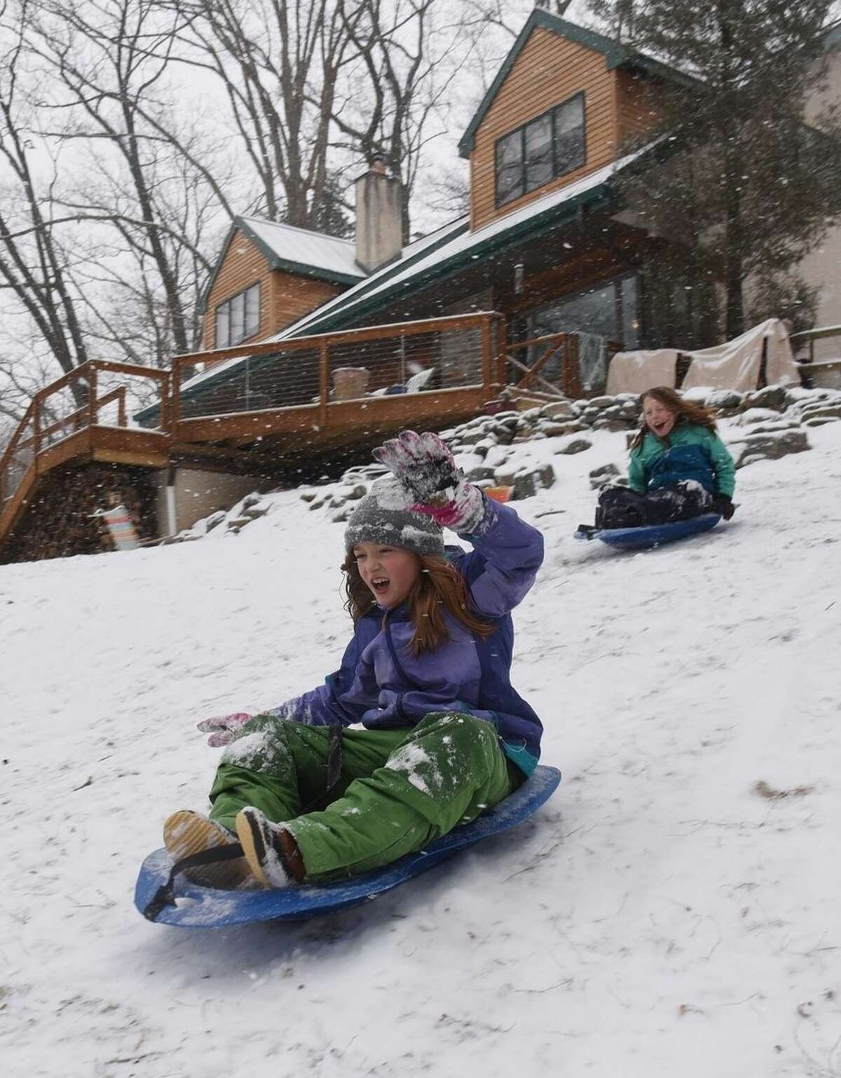 Phoebe Davidson, front, 9, and her friend Helena McConatha Rosle, 10, slide down the hill in front of Phoebe's house Monday, Feb. 15, 2016, in Media, Pa. (Clem Murray/The Philadelphia Inquirer via AP)