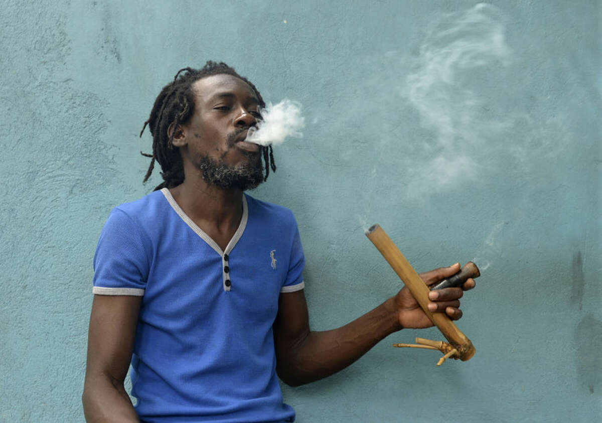 A Jamaican Rastafarian known as Nature smokes marijuana outside the Trench Town Culture Yard Museum in downtown Kingston, Jamaica, Wednesday, April 15, 2015, where he works as a tour guide. Nature, like most adherents of the Rastafarian movement, said he smokes for spiritual purposes. Drug law amendments decriminalizing small amounts of pot and paving the way for a lawful medical marijuana sector came into effect Wednesday in Jamaica. (AP Photo/David McFadden)