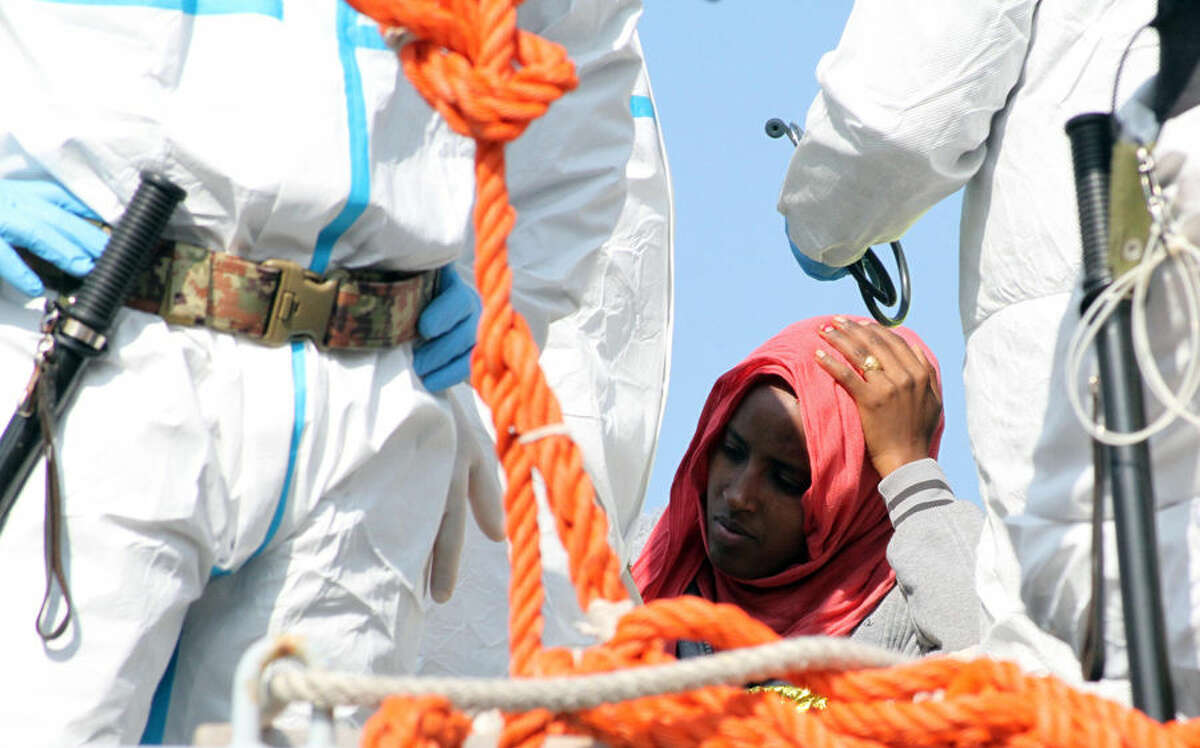 In this picture taken on Tuesday, April 14, 2015 a woman waits to disembark from an Italian Navy vessel in the harbor of Reggio Calabria, southern Italy. The precise number of migrants who have perished in the Mediterranean sea as they flee poverty, war and other conflicts in Africa, the Middle East and Asia is unknown. Only the bodies that wash ashore or are found drowned in the sea or dead aboard, of thirst or exposure, by rescuers are counted. (AP Photo/Adriana Sapone)