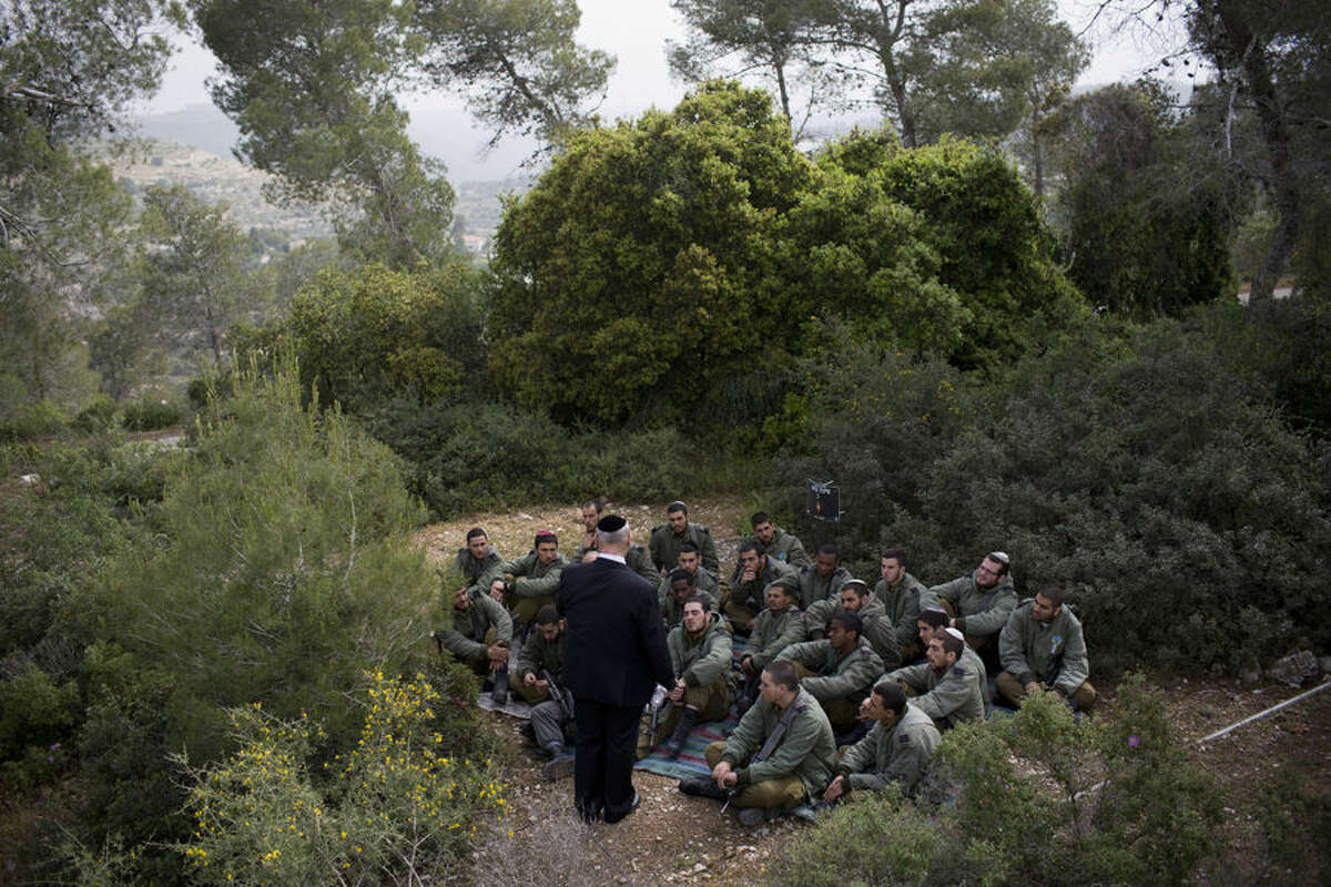 Moshe Eshkenazi, tells Israeli border police officers the story of his grandfather Moshe Pesach, rabbi of the Jewish community in Volos during World War II who saved more than one thousand Jews, during a ceremony marking the annual Holocaust remembrance day in the Martyr's forest near Moshav Kesalon, in central Israel, Thursday, April 16, 2015. Sirens sounded across Israel on Thursday morning, bringing life to a standstill as millions of Israelis observed a moment of silence to honor the memory of the 6 million Jews killed in the Nazi Holocaust during World War II. (AP Photo/Oded Balilty)