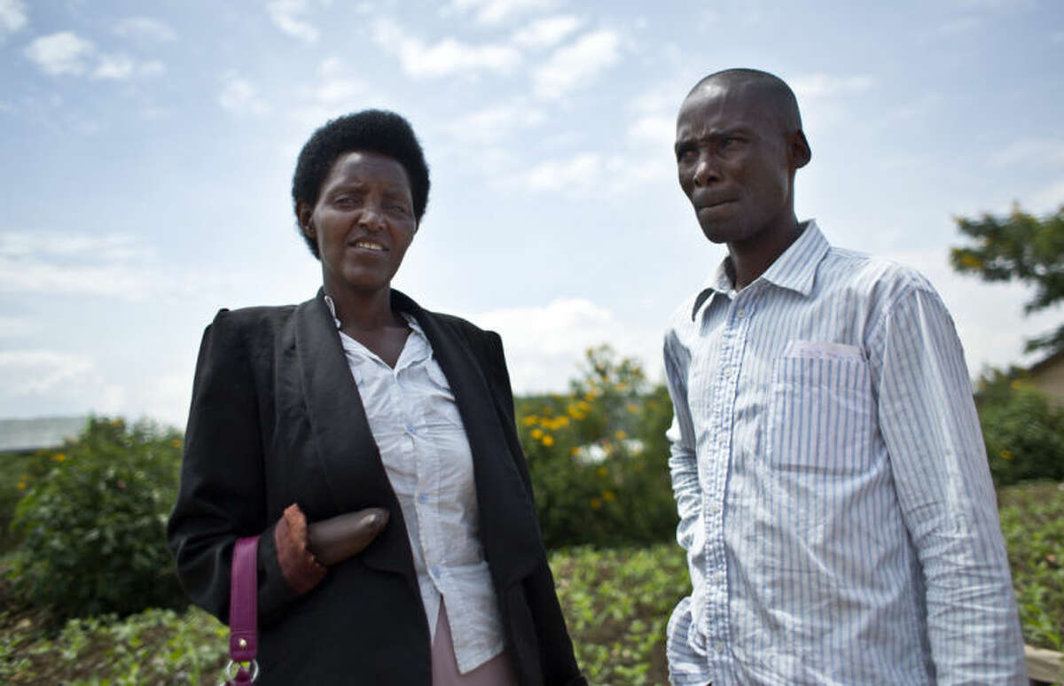 In this photo taken Wednesday, March 26, 2014, Emmanuel Ndayisaba, right, and Alice Mukarurinda, pose for a photograph outside Alice's house in Nyamata, Rwanda. She lost her baby daughter and her right hand to a manic killing spree. He wielded the machete that took both. Yet today, despite coming from opposite sides of an unspeakable shared past, Alice Mukarurinda and Emmanuel Ndayisaba are friends. She is the treasurer and he the vice president of a group that builds simple brick houses for genocide survivors. They live near each other and shop at the same market. Their story of ethnic violence, extreme guilt and, to some degree, reconciliation is the story of Rwanda today, 20 years after its Hutu majority killed more than 1 million Tutsis and moderate Hutus. The Rwandan government is still accused by human rights groups of holding an iron grip on power, stifling dissent and killing political opponents. But even critics give President Paul Kagame credit for leading the country toward a peace that seemed all but impossible two decades ago. (AP Photo/Ben Curtis)
