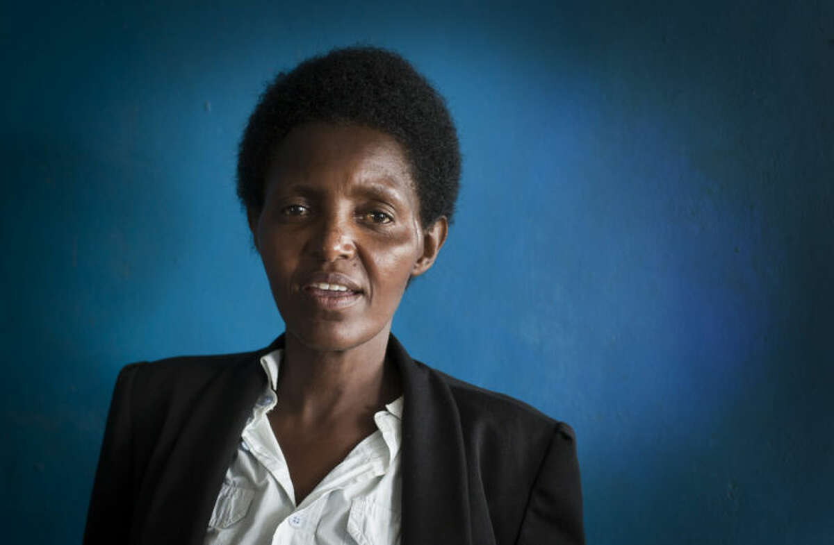 In this photo taken Wednesday, March 26, 2014, Alice Mukarurinda, poses for a photograph at her house in Nyamata, Rwanda. She lost her baby daughter and her right hand to a manic killing spree. Emmanuel Ndayisaba wielded the machete that took both. Yet today, despite coming from opposite sides of an unspeakable shared past, Alice Mukarurinda and Emmanuel Ndayisaba are friends. She is the treasurer and he the vice president of a group that builds simple brick houses for genocide survivors. They live near each other and shop at the same market. Their story of ethnic violence, extreme guilt and, to some degree, reconciliation is the story of Rwanda today, 20 years after its Hutu majority killed more than 1 million Tutsis and moderate Hutus. The Rwandan government is still accused by human rights groups of holding an iron grip on power, stifling dissent and killing political opponents. But even critics give President Paul Kagame credit for leading the country toward a peace that seemed all but impossible two decades ago. (AP Photo/Ben Curtis)