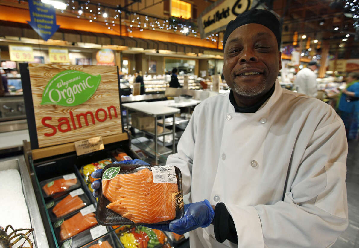 Cooking coach Chef Charles Hill poses for a picture as he holds a Canadian certified organic farm-raised King Salmon at the Wegmans, Friday, April 10, 2015 in Fairfax, Va. Organic fish is certified in the EU and Canada because the US doesn’t have any standard. After more than a decade of delays, the government is moving toward allowing the sale of U.S.-raised organic fish and shellfish. But don't expect it in the grocery store anytime soon. (AP Photo/Alex Brandon)