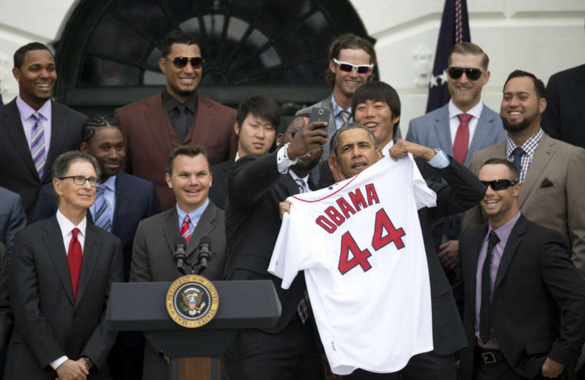 Boston Red Sox designated hitter David "Big Papi" Ortiz takes a selfie with President Barack Obama, holding a Boston Red Sox jersey presented to the president, on the South Lawn of the White House in Washington, Tuesday, April 1, 2014, during a ceremony where the president honored the 2013 World Series baseball champion Boston Red Sox. From left are, principal owner John W. Henry, Executive Vice President - General Manager Ben Cherington, pitchers Junichi Tazawa, Ortiz, the president, and pitcher Koji Uehara. Top left is infielder Xander Bogaerts. (AP Photo/Carolyn Kaster)