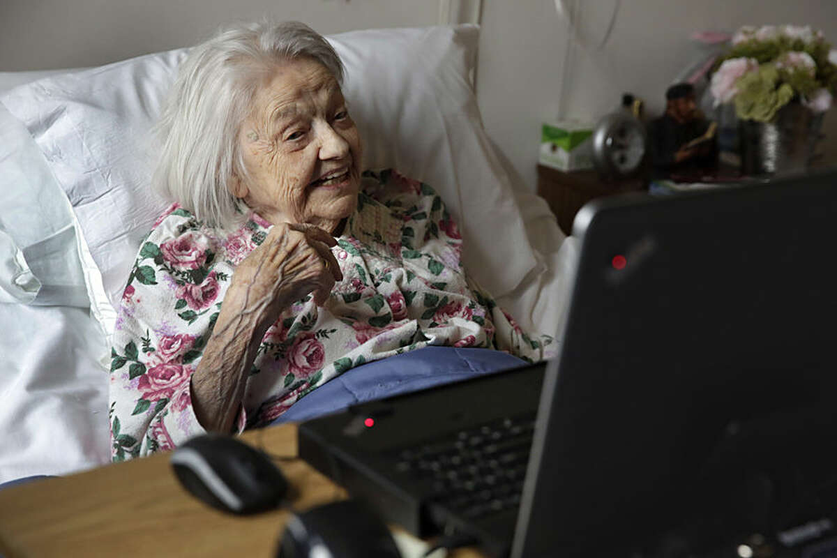 Patient Louise Irving watches a laptop computer with her daughter's morning wake-up video playing, at The Hebrew Home of Riverdale, in New York, Wednesday, March 25, 2015. The nursing home in the Bronx has started a pilot program in which relatives record video messages for patients of Alzheimer's and other forms of dementia. The videos are played for them each morning to calm their agitation and reassure them about their surroundings and their routines. (AP Photo/Richard Drew)