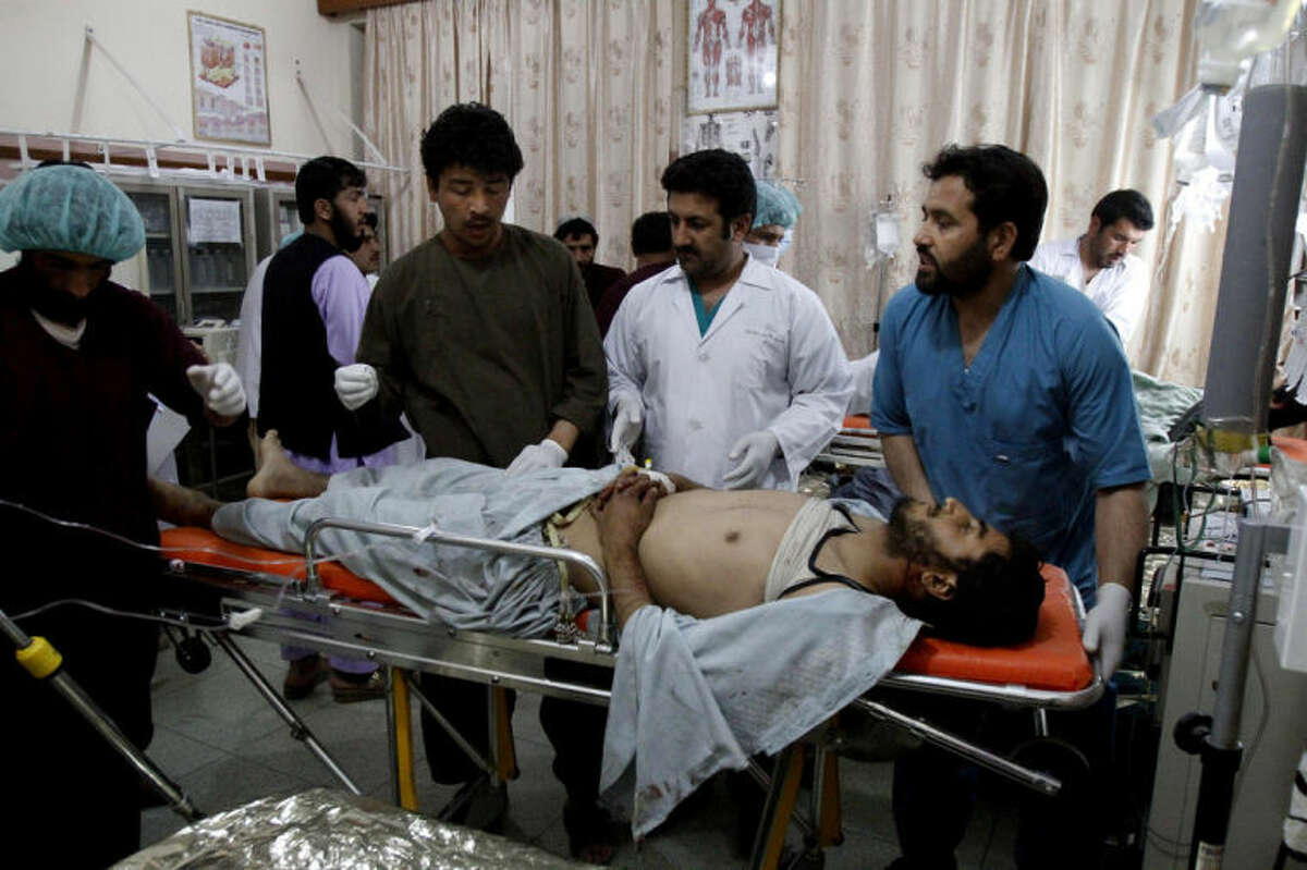 Afghan doctors and medics treat a wounded man at a hospital after a roadside bomb in Kandahar, south of Kabul, Afghanistan, Monday, April 7, 2014. A roadside bomb killed at least 15 people traveling in vehicles that had been diverted from a main road Monday after an earlier attack in southern Afghanistan, officials said. (AP Photo/Allauddin Khan)