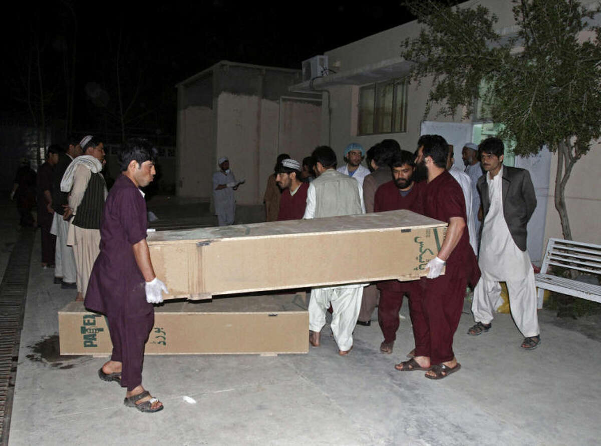 Hospital staff carry the coffin of a person killed from a roadside bomb, at a hospital in Kandahar, south of Kabul, Afghanistan, Monday, April 7, 2014. A roadside bomb killed at least 15 people traveling in vehicles that had been diverted from a main road Monday after an earlier attack in southern Afghanistan, officials said. (AP Photo/Allauddin Khan)