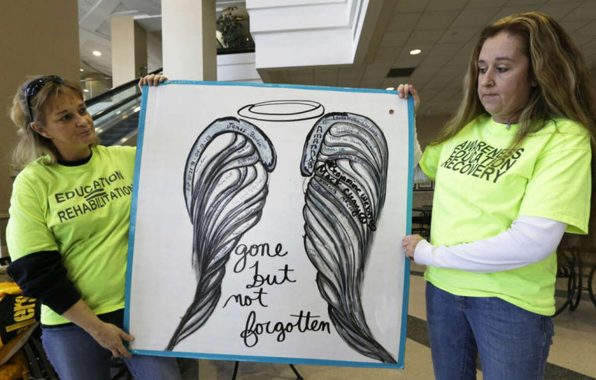 In this Monday, Feb. 10, 2014 photo, Candy Murray Abbott, left, and Tammie Norris hold a sign made by Norris that shows a pair of angel's wings with the names of youths who have died from drug abuse in Hamilton, Ohio. The two mothers, who both have a child that is a recovering addict, formed a group called Heroin Control in Hamilton. "If you stood next to somebody and just started a conversation about heroin, you'd hear: 'Oh yeah, my nephew's on heroin. My next-door neighbor's on heroin. My daughter's on heroin,'" says Abbott, who helped her own 27-year-old son through withdrawal in summer 2013. (AP Photo/Al Behrman)