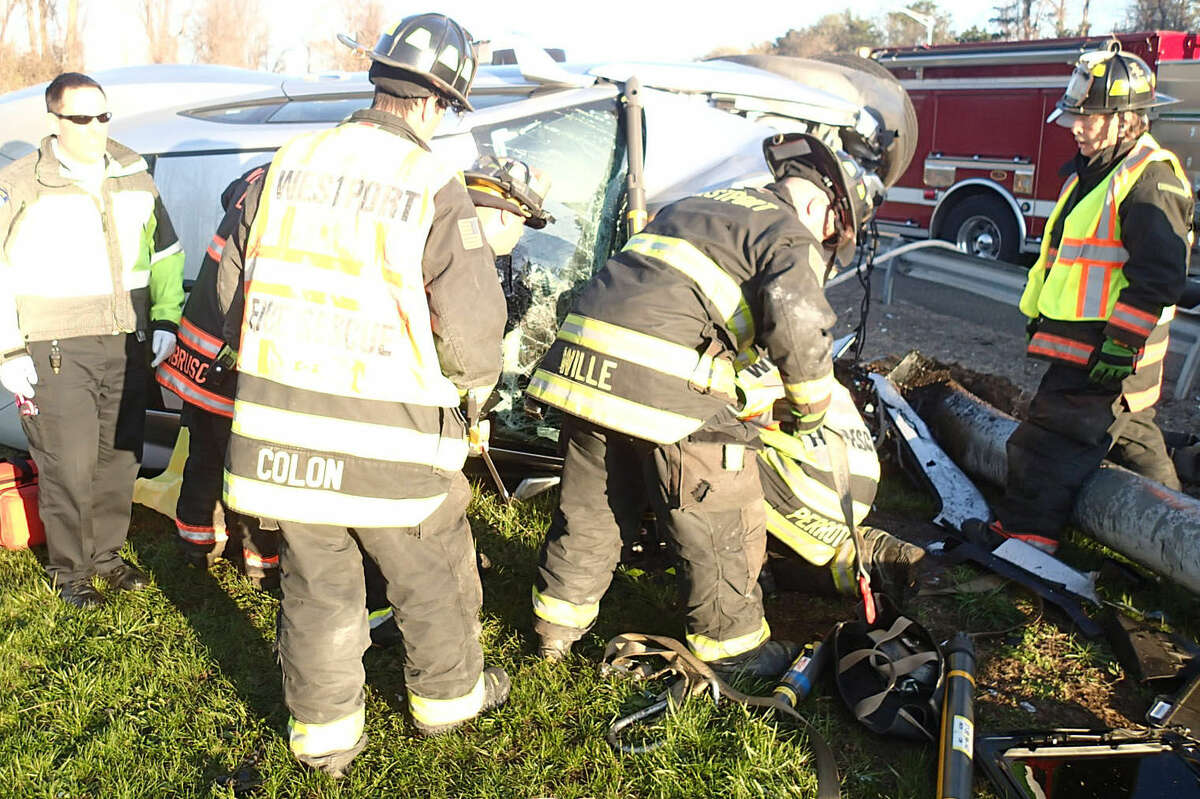 Firefighters work to remove the driver from a car that struck a pole on Interstate 95 and flipped on its side Saturday morning.